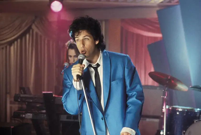 Adam Sandler sings dressed in blue in The Wedding Singer, one of Loud and Clear Reviews' top 10 Adam Sandler movies ranked from worst to best