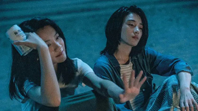 Two girls sit next to each other with beer cans in Who'll Stop the Rain, one of the 10 films to watch at BFI Flare 2024 according to Loud and Clear Reviews