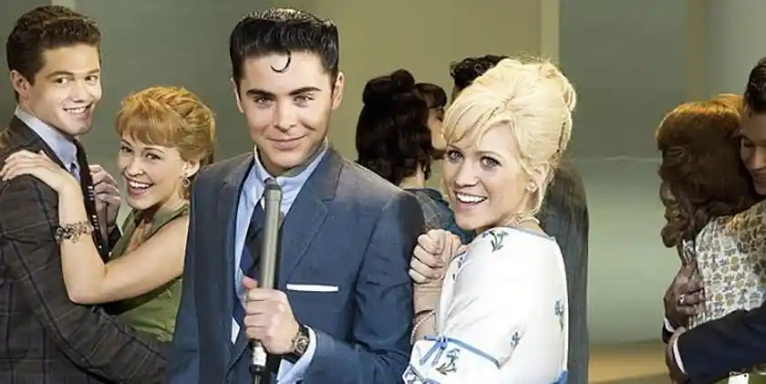 Zac Efron holds a microphone in Hairspray