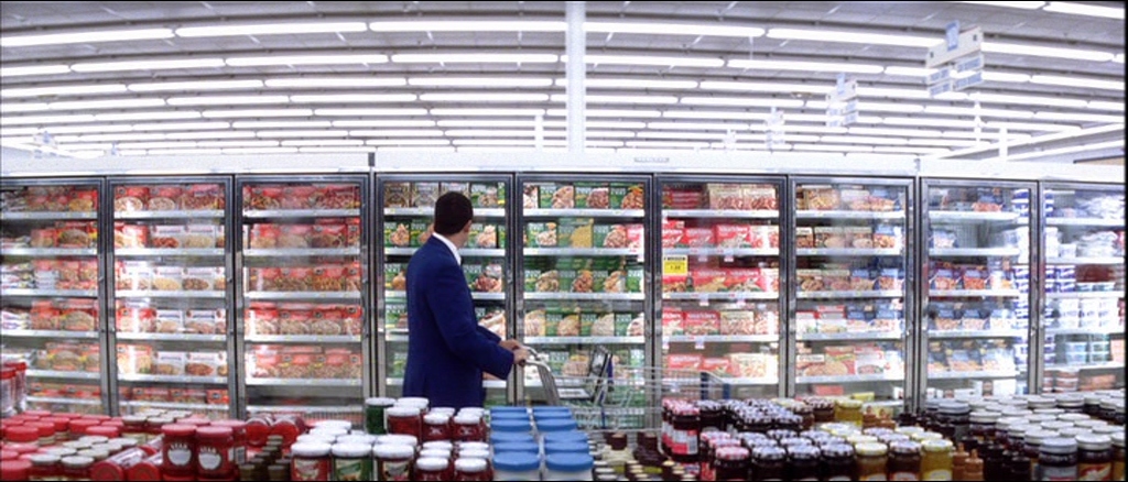 Barry Egan holds a shopping trolley at the supermarket, looking at frozen food, in the film Punch-Drunk Love