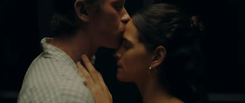 Garrett Hedlund kisses Adria Arjona on the forehead, in the dark, in political film The Absence of Eden