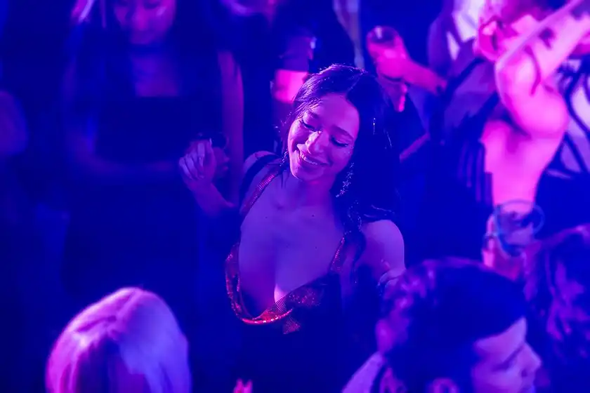 A woman with long black hair wears a red dress and dances on the dancefloor in the movie Anora, one of the 20 films to watch at the 2024 Cannes film festival according to Loud and Clear Reviews