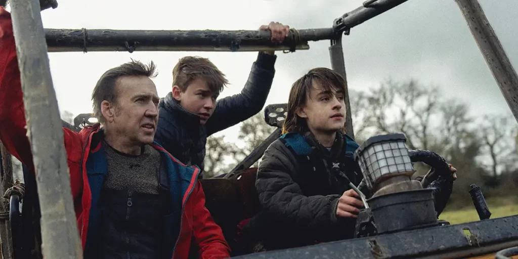 Nicolas Cage and his character's two children look in front of them from a vantage point in the film Arcadian