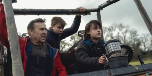 Nicolas Cage and his character's two children look in front of them from a vantage point in the film Arcadian