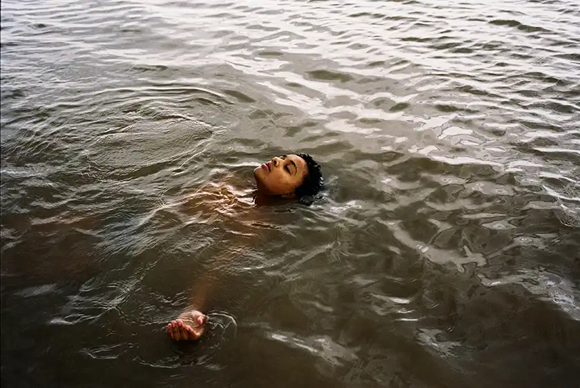 A black man lies in the water face up in the film Bird