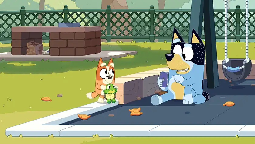 Bingo holds a turtle while Bluey is using her phone in the episode "Turtleboy", one of the 5 Best Episodes of Bingo according to Loud and Clear Reviews