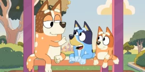 Three main characters of the series Bluey sit on a bench