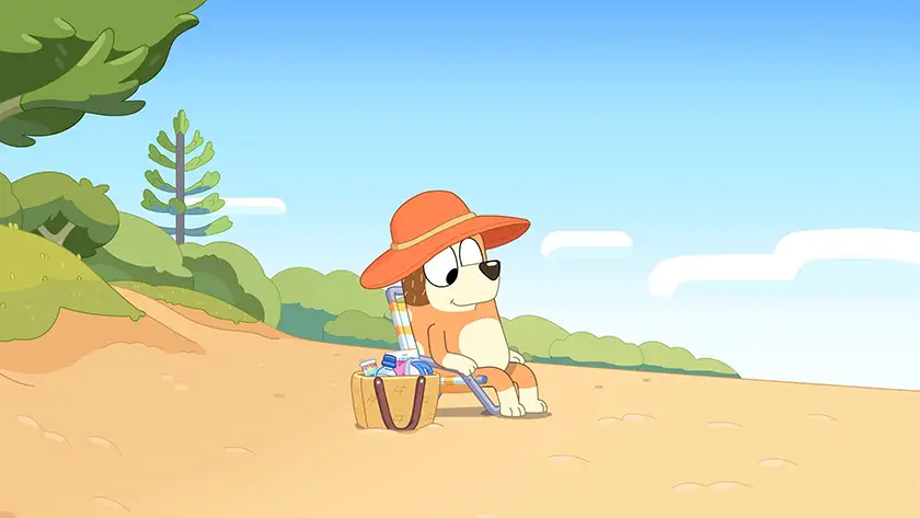 Chilli sits on a chair on the beach in one of the 5 Best Episodes of Bluey according to Loud and Clear Reviews