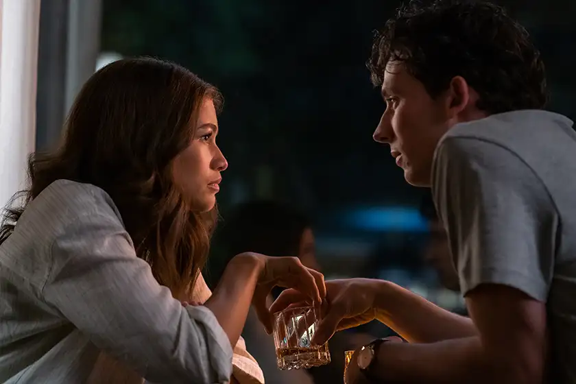 Zendaya as Tashi and Josh O’Connor as Patrick look at each other holding glasses at night in the 2024 film Challengers