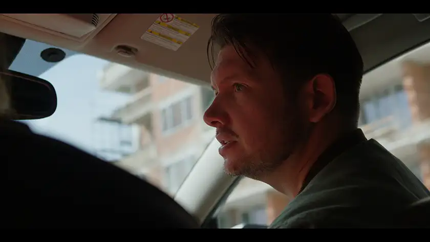 Director Colin Archdeacon sits inside a car and looks to his left with wide eyes in the Paramount+ series CTRL+ALT+DESIRE