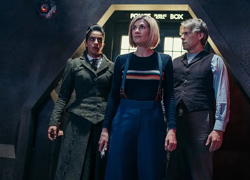 The doctor and two people stand in front of a door looking around in the special episode of Doctor Who anticipating Season 14