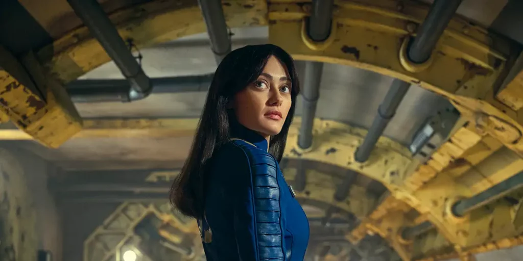 Ella Purnell turns around standing underneath an arc in Prime Video series Fallout