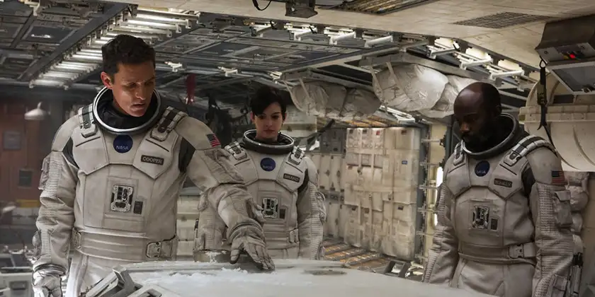 Three astronauts point at a map inside a spaceship in the movie Interstellar