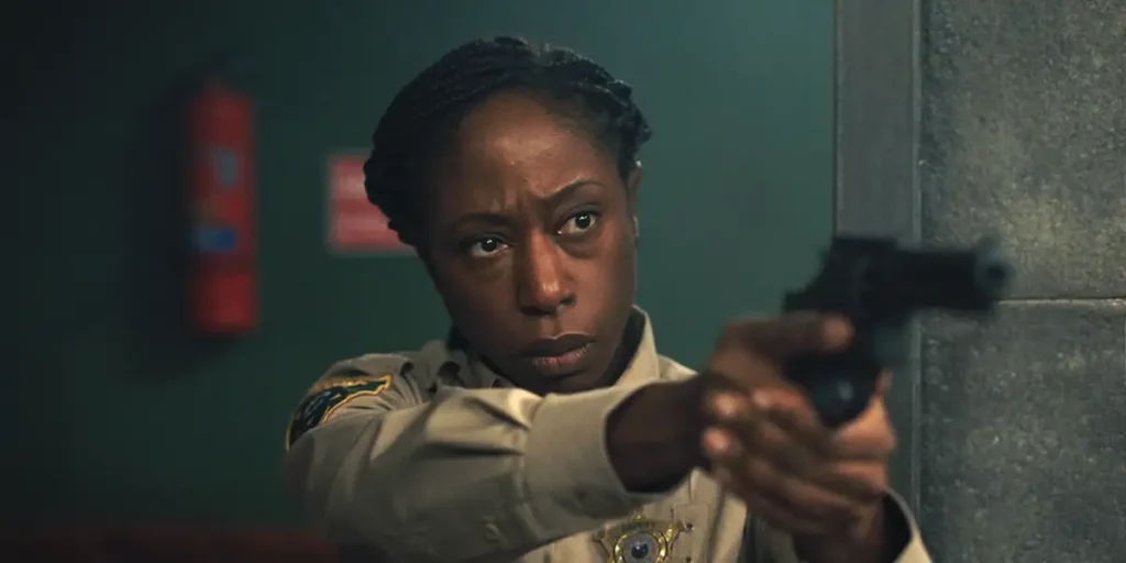 A Black policewoman holds a gun pointing it at someone in the film Jericho Ridge