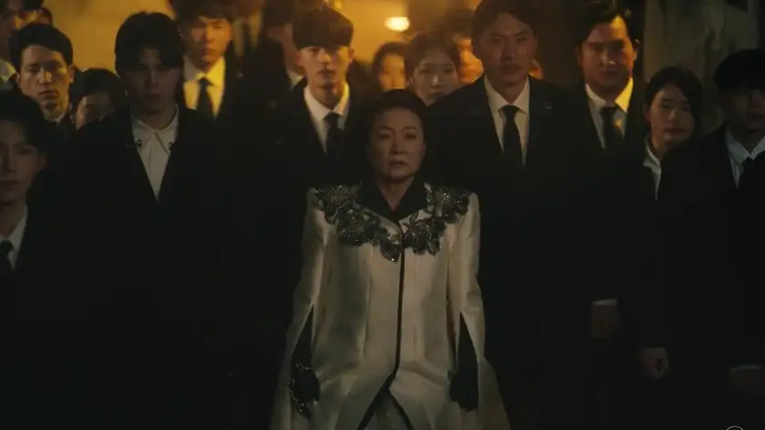 A woman in white stands in the middle of men and women wearing tuxedos in a still from "Tomorrow", one of the K-Dramas that tell better stories than western media according to Loud and Clear Reviews