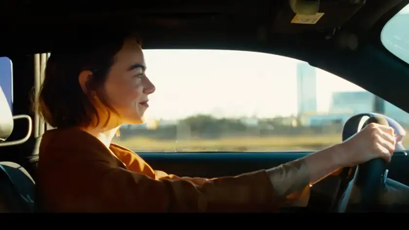Emma Stone is driving in a still from Kinds of Kindness, featured in an article with everything we know about the movie