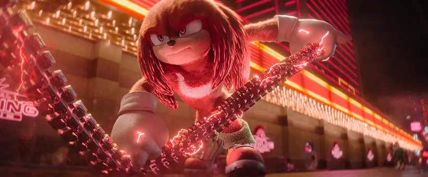 The character Knuckles, from the game Sonic the Hedgehog, holds a chain while using his lightning power in front of a building with neon lights