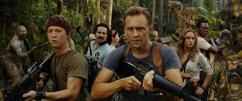 Tom Hiddleston holds a rifle in Kong: Skull Island with his team behind him, in the forest