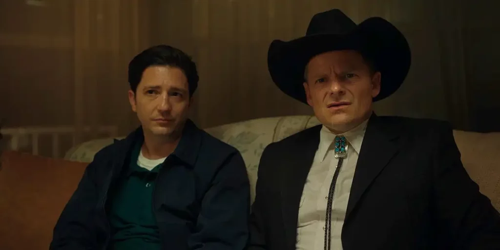 John Magaro and Steve Zahn sit on a couch next to each other in the film Laroy Texas