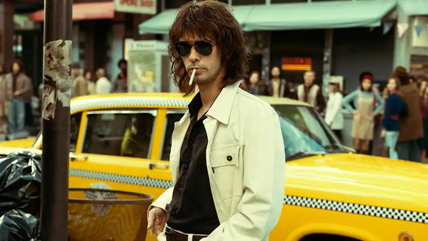 Ben Whishaw smokes a cigarette wearing Ray Ban and leaning on a taxi in the movie Limonov, one of the 20 films to watch at the 2024 Cannes film festival according to Loud and Clear Reviews