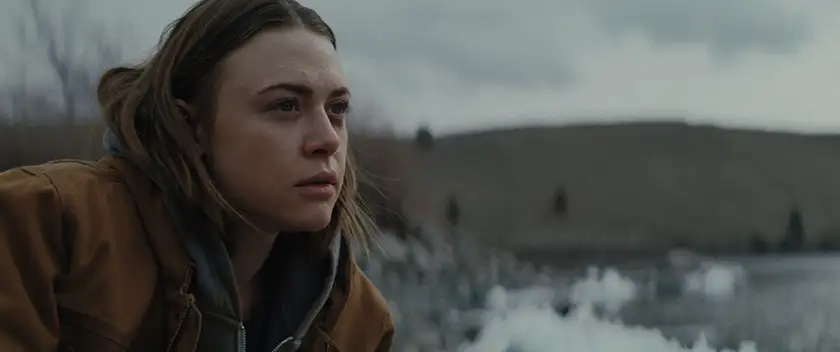 A young woman wears a brown jacket in the mountains, looking in front of her, in the 2024 film New Life
