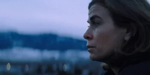 The face of a brown haired woman with blue eyes is seen on the right of the frame, looking ahead, with the mountains behind her, in the 2024 film New Life