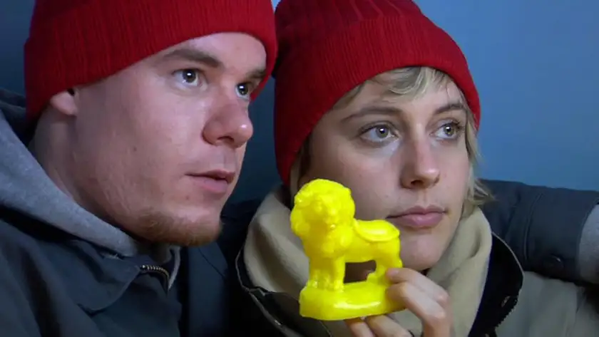 Joe Swanberg and Greta Gerwig hold a yellow toy lion wearing red hats in Nights and Weekends, one of the movies directed by Greta Gerwig ranked from worst to best by Loud and Clear Reviews