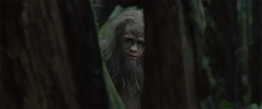 Riley Keough emerges from behind some trees in the 2024 film Sasquatch Sunset