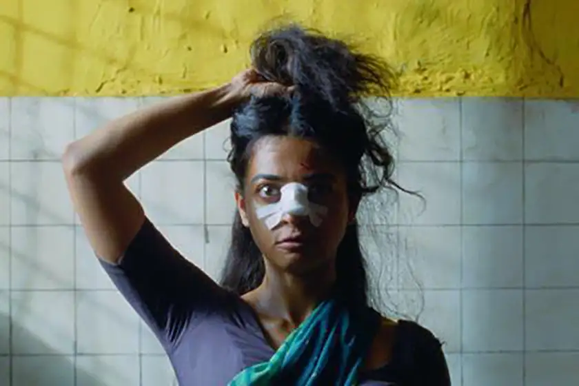 An indian woman holds her hair up in a bathroom, with a broken nose, in the movie Sister Midnight, one of the 20 films to watch at the 2024 Cannes film festival according to Loud and Clear Reviews