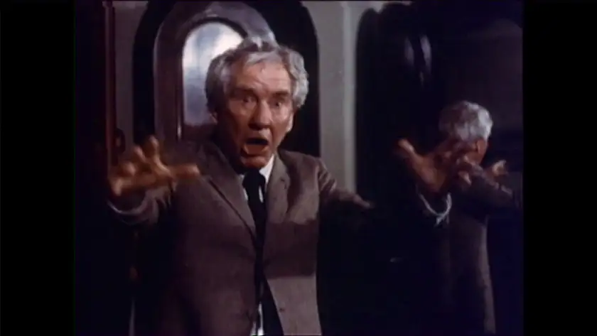 An old man makes a crazy posed showing his hands in the film The Sentinel
