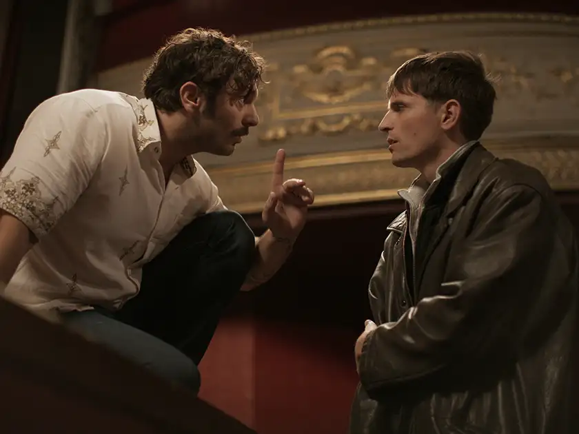 A man on a theatre stage points a finger at another man in front of him in the film Yannick