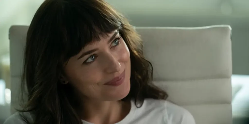 Dakota Johnson smiles looking to her left, wearing a white shirt, in the Max film Am I OK?