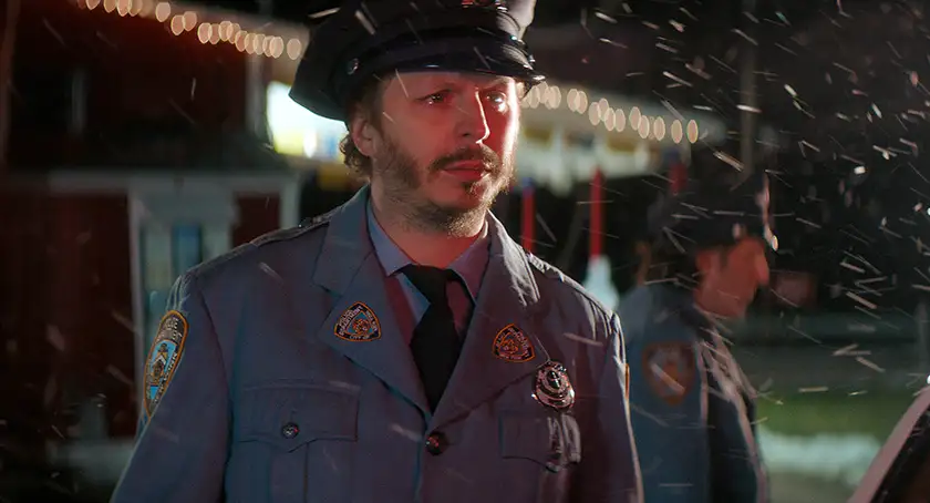 Michael Cera stands dressed as a policeman in the snow at night  in the Tyler Taormina film Christmas Eve in Miller's Point, featured in the Loud and Clear interview