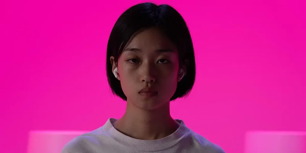 A japanese girl looks at the camera on a pink background in the film Desert of Namibia