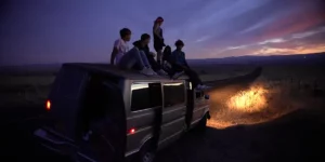 Some teenagers stand on the roof of a van at night in the film Gasoline Rainbow