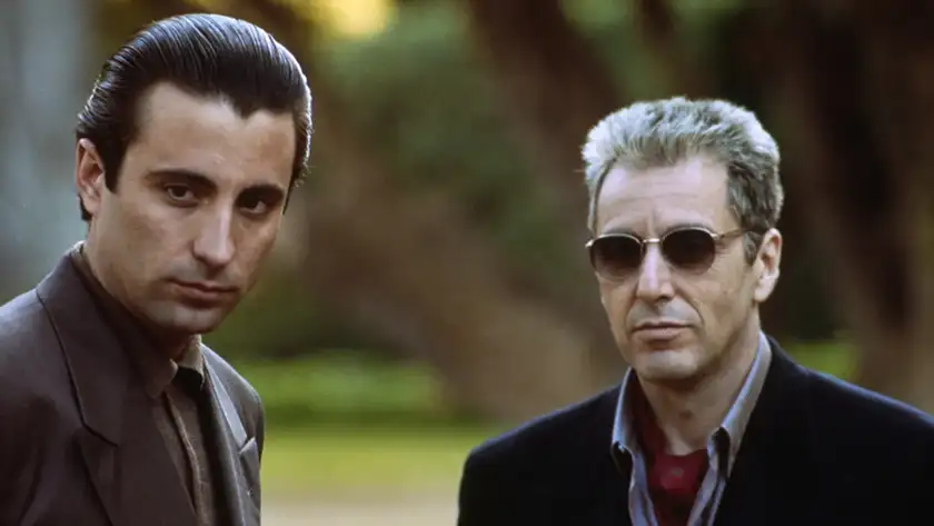 Two men stand looking in front of them, the older one on the right wearing sunglasses, in The Godfather Part III, one of all Francis Ford Coppola movies ranked from worst to best by Loud and Clear Reviews 