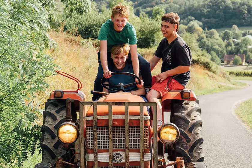 Three boys drive a tractor in the film Holy Cow (Vingt Dieux)