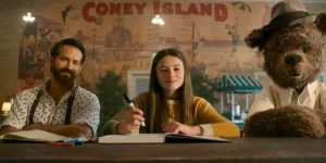 A man, a girl, and a bear lean on a desk looking at the camera in the film IF