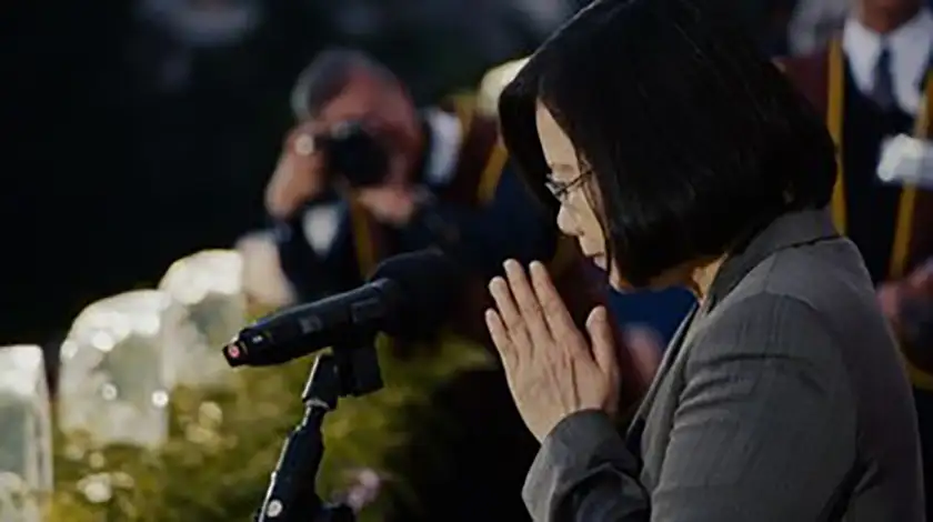 Taiwan president Tsai Ing-wen makes a gesture of prayer in front of a microphone in the film Invisible Nation