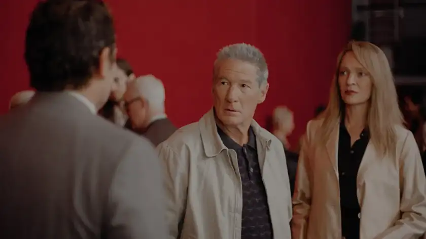 Richard Gere and Uma Thurman, two of the 5 reasons to be excited about Paul Schrader's film Oh, Canada, stand in front of a red wall talking to someone in a still from the movie