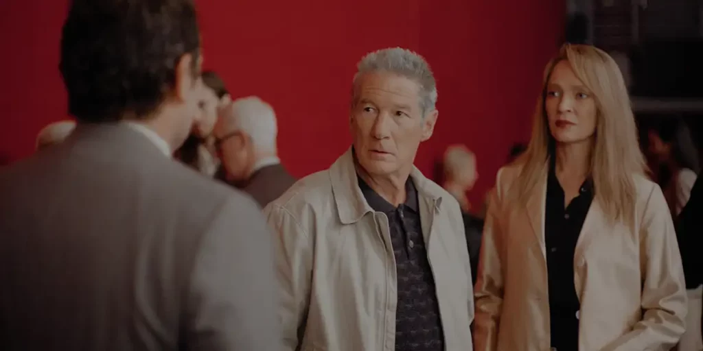 Uma Thurman and Richard Gere talk to someone in front of a red wall in the Paul Schrader film Oh, Canada