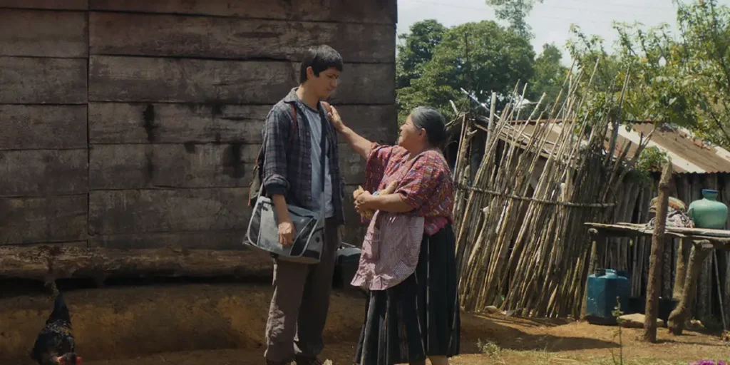 A tall young man stands in front of his grandma, who has a hand on his shoulder in affection, in the film Our Mothers