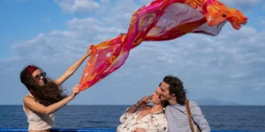 A woman weaves a scarf in the air by the sea in a still from Paolo Sorrentino's film Parthenope