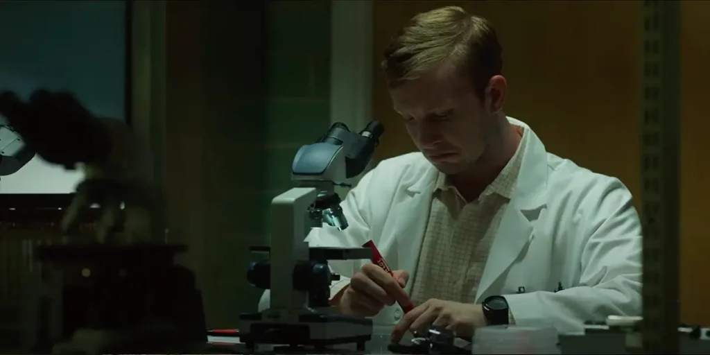 A doctor looks down a microscope holding a pen in the film Protocol-7