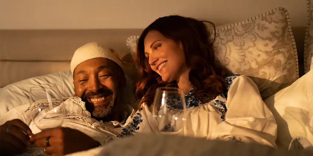 A man and a woman are in bed, smiling, in the 2024 film Re: Uniting