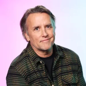Richard Linklater smiles in front of a pink and blue background (credit: Getty for Imdb)