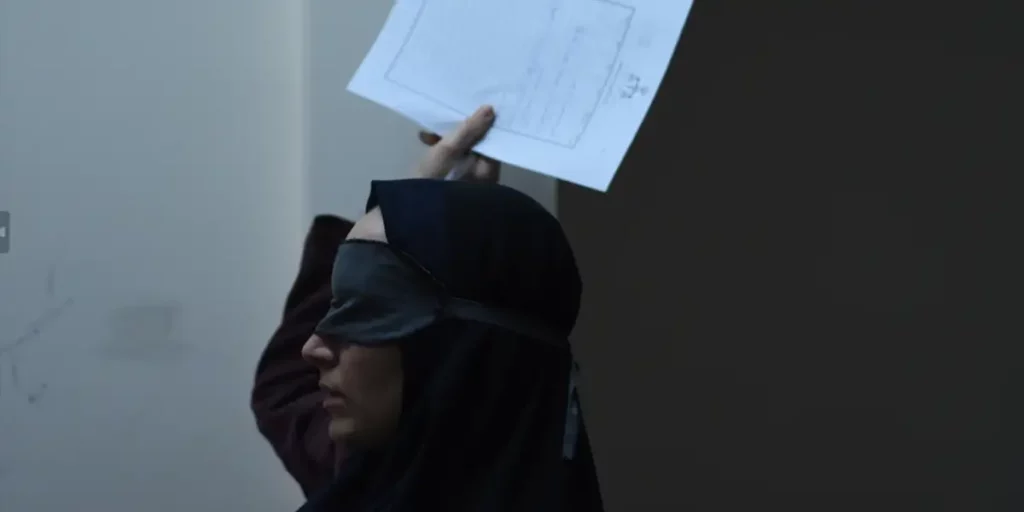 A woman with a black mask on her face holds some papers over her head in The Seed of the Sacred Fig