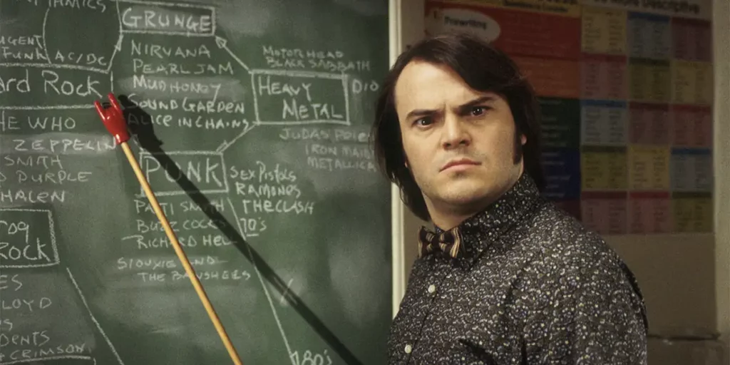 Jack Black points at a blackboard with a stick that points to the word "rock" in the film School of Rock
