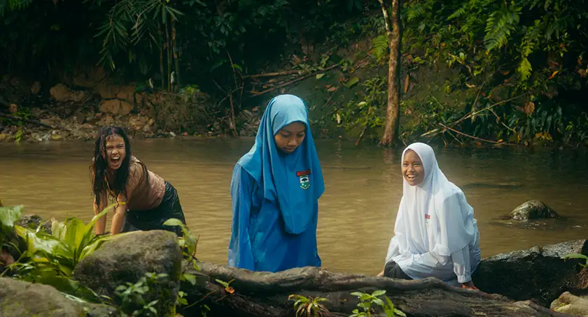A girl is in the water and two other girls are near her in the film Tiger Stripes