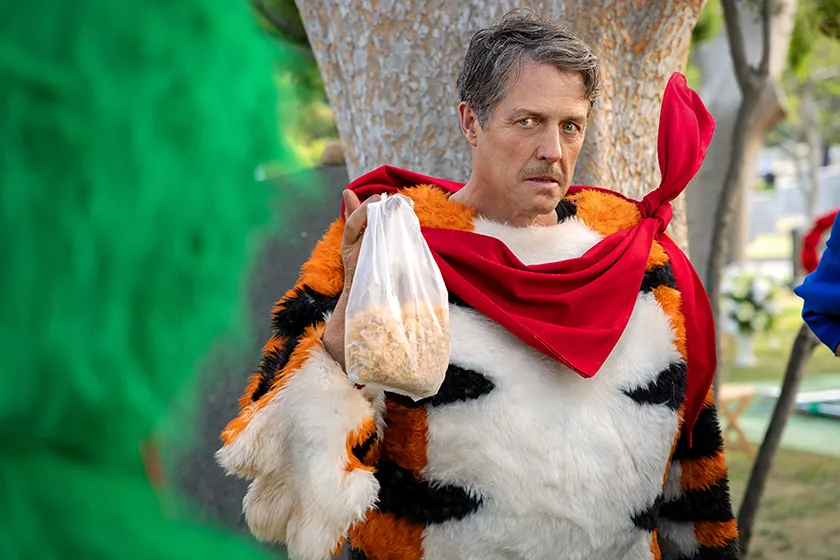 Hugh Grant holds a bag of frosties looking angry dressed as Thurl in the Netflix film Unfrosted